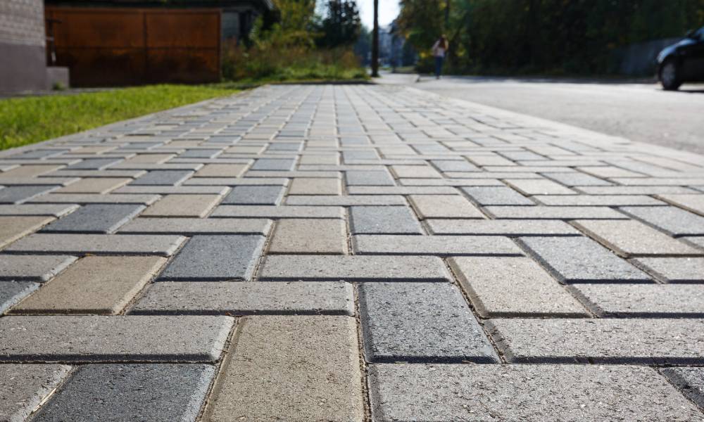 Paved pedestrian walkway with sunlight and approaching figure.