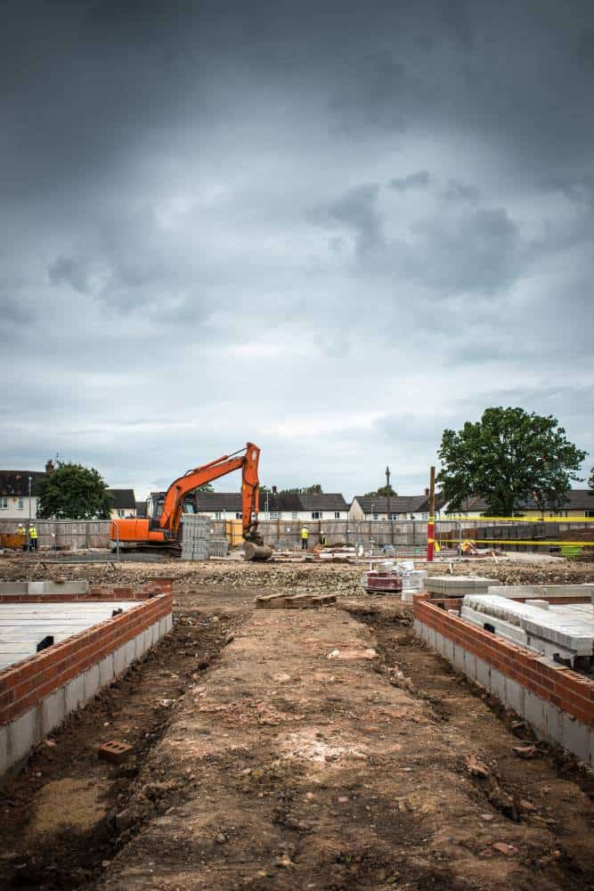 Construction site with excavator under cloudy sky.