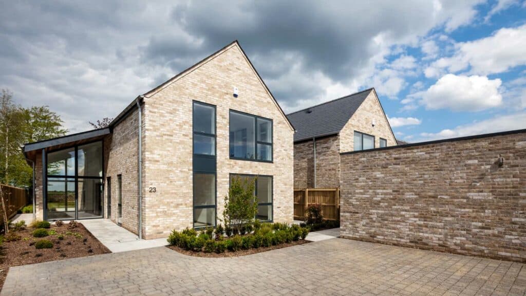 Modern brick house with large windows and paved driveway.