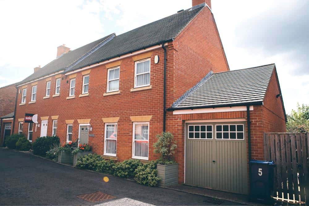 Detached brick house with sold sign and garage in UK.