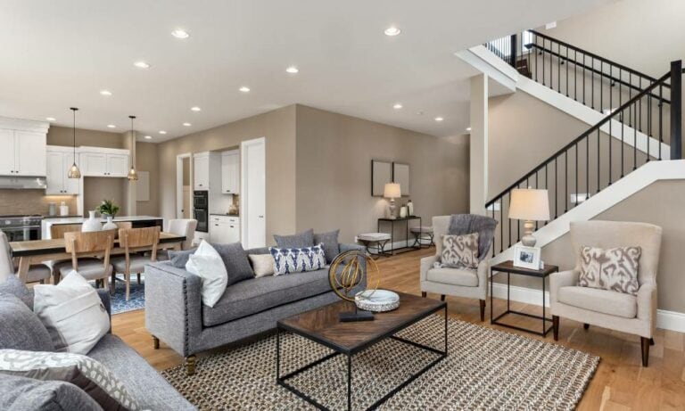 Modern open-plan living room with staircase and kitchen.