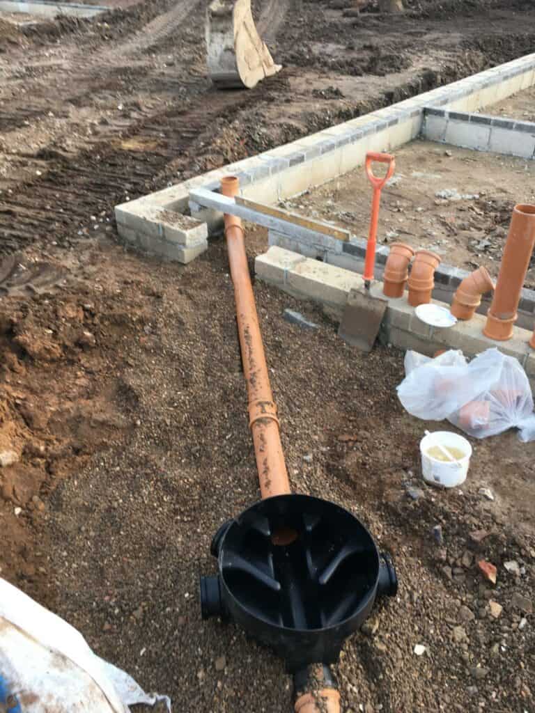 Construction site with drainage installation in progress.