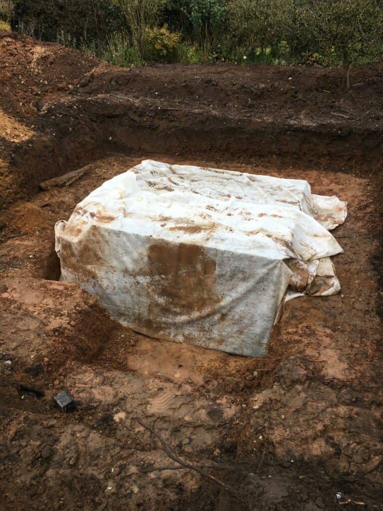 Large tarp-covered object in excavation pit