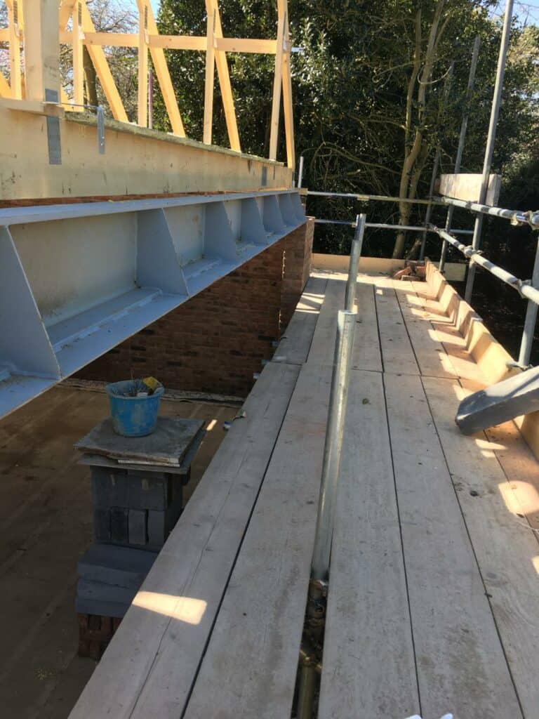 House extension construction site with scaffolding and beams.