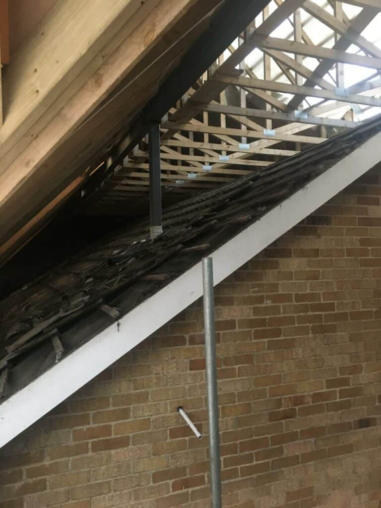 Exposed wooden beams and damaged roof interior.