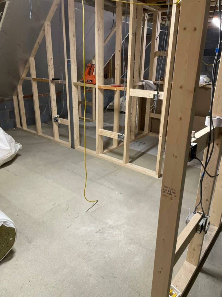 Wooden stud framing in unfinished basement construction.