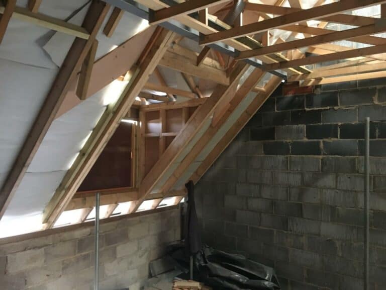 Unfinished attic space with exposed rafters and insulation.