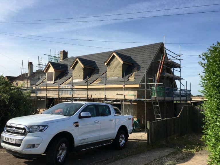 House under construction with scaffolding and pickup truck.