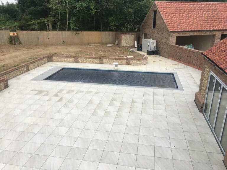 Backyard with tiled patio and swimming pool.