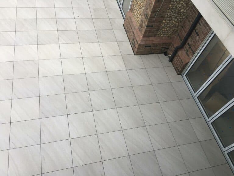 Tiled floor with brick wall corner and glass door.