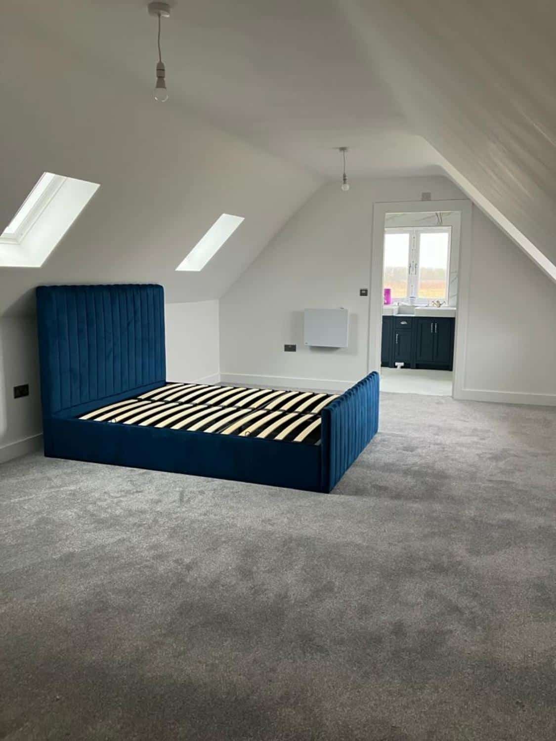 Spacious modern attic bedroom with blue bed.