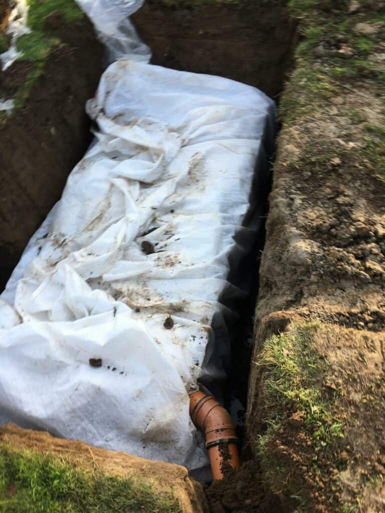 Underground pipe repair in trench with protective covering.