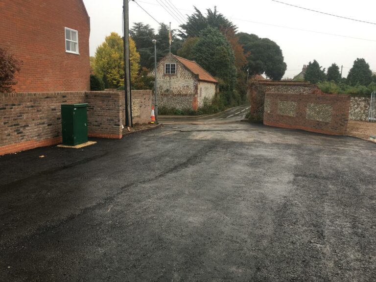 Freshly paved empty parking area with brick walls