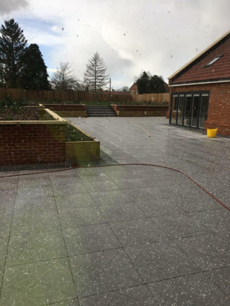 Rainy courtyard with brick building and trees.