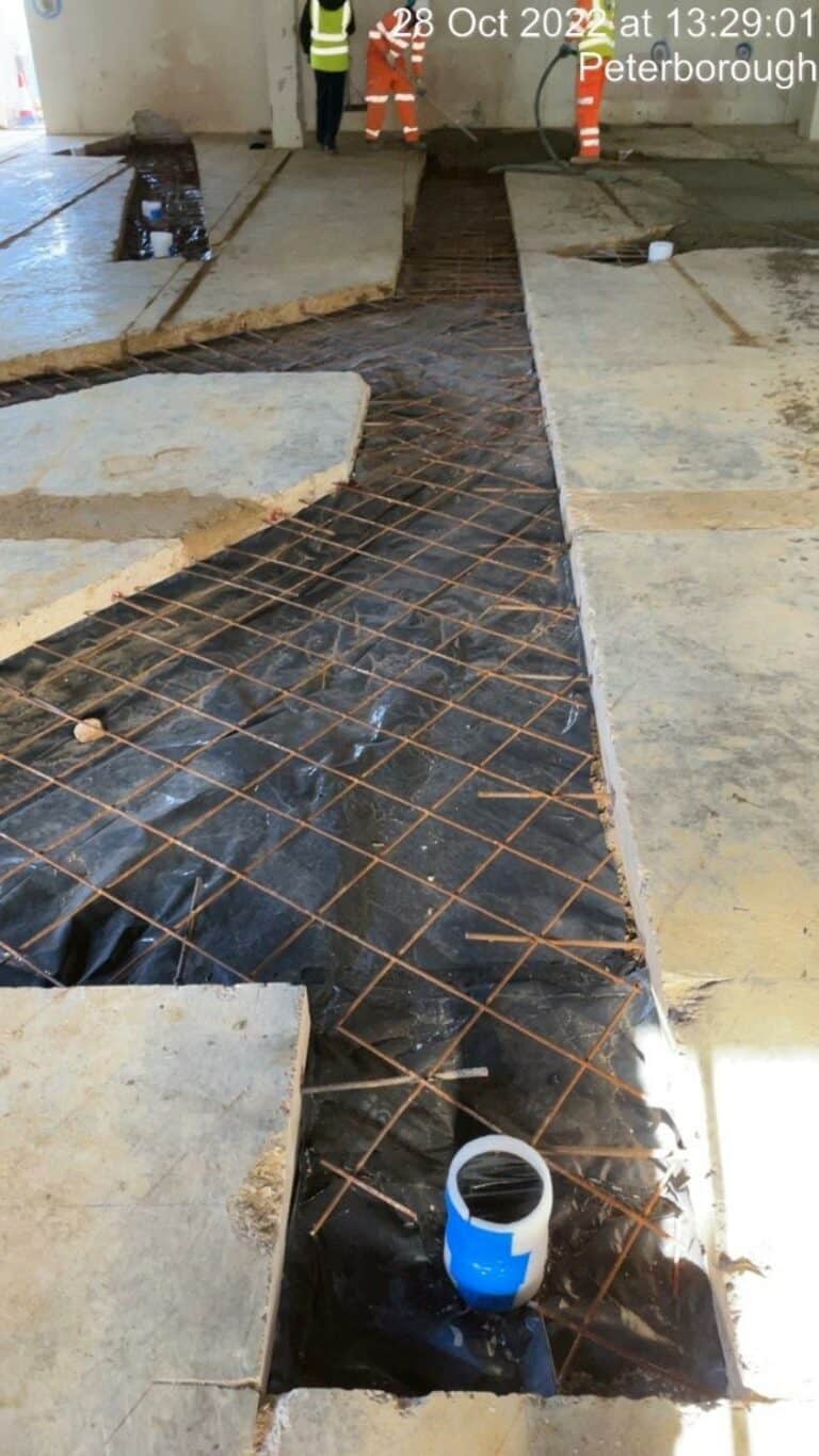 Construction workers laying rebar for concrete floor.