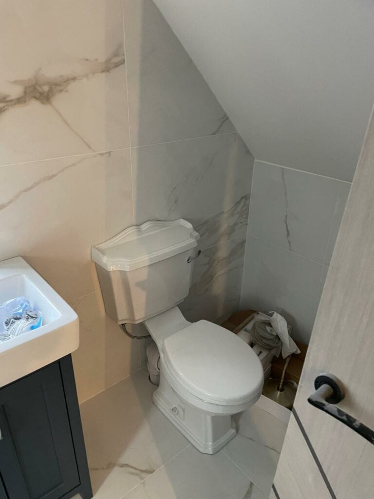 Modern bathroom with marble tiles and white fixtures.