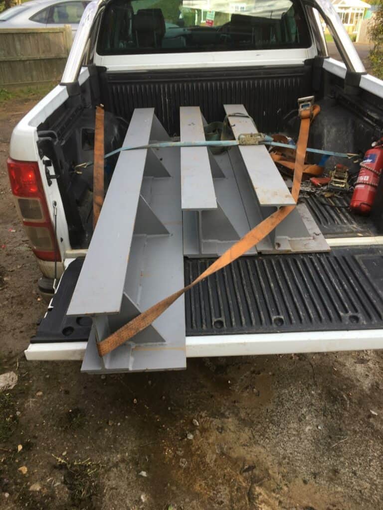 Steel beams secured in pickup truck bed.