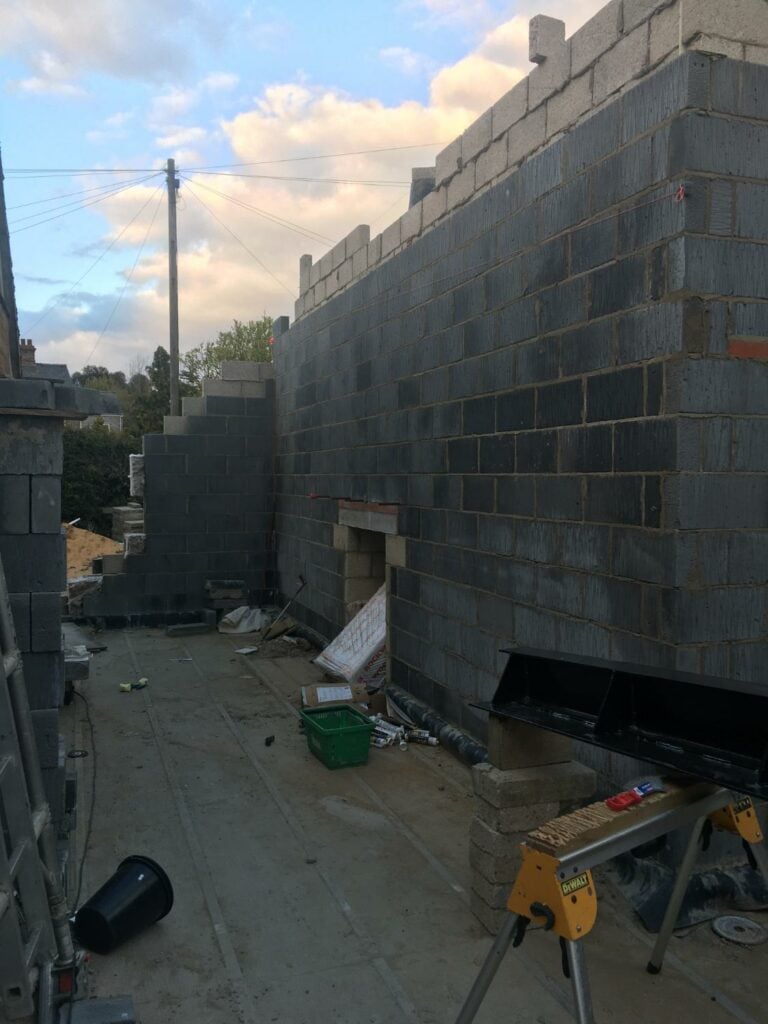 Construction site with unfinished blockwork and building materials.