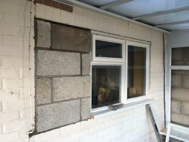 House exterior with incomplete brickwork repair near window.