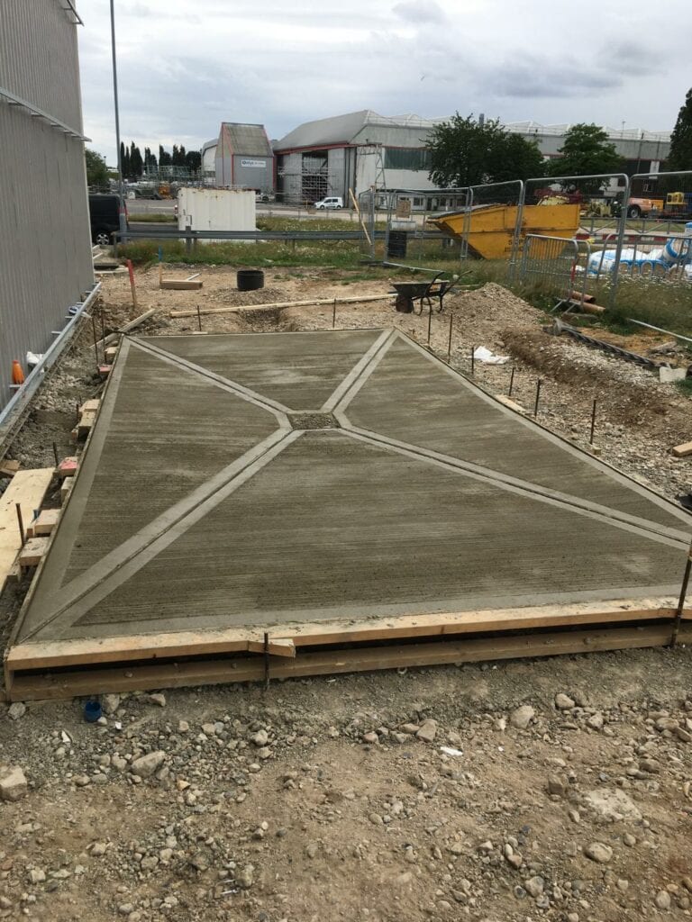 Fresh concrete foundation at industrial construction site.