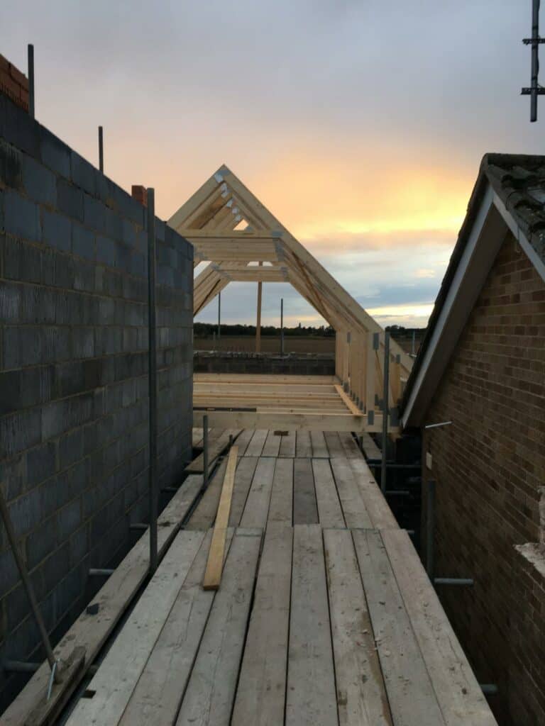 Construction site with wooden roof structure at sunset