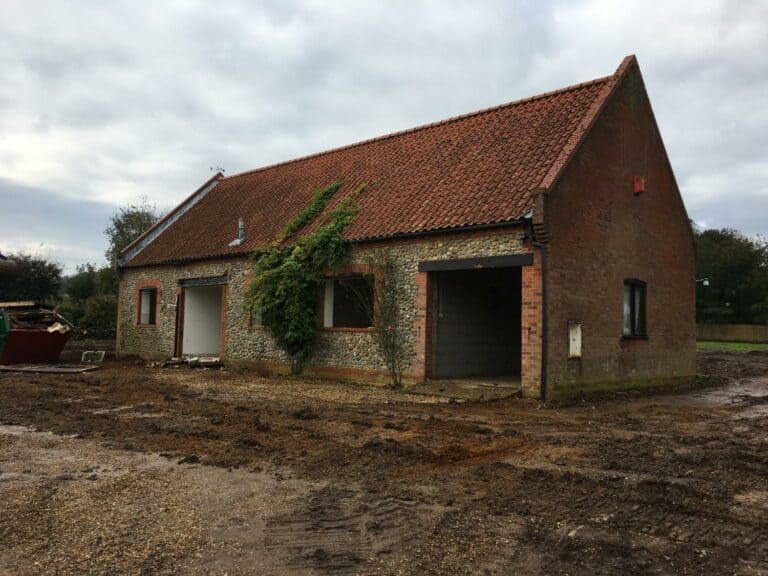 Renovating old brick barn with overgrown ivy.