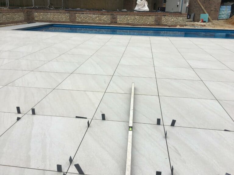 Patio tile installation near swimming pool.