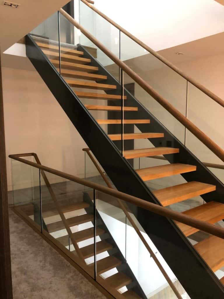 Modern wooden staircase with glass balustrade.