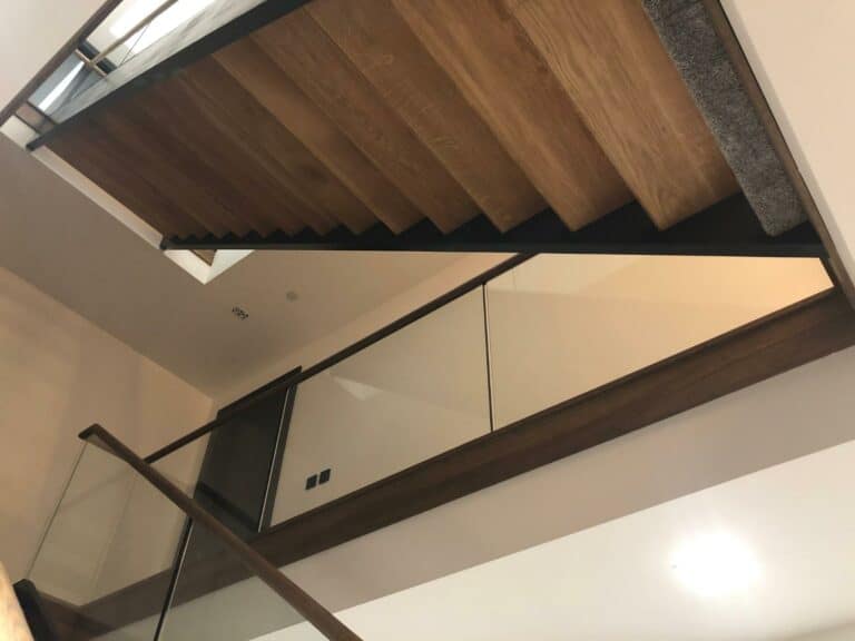 Modern wooden staircase with glass balustrade.