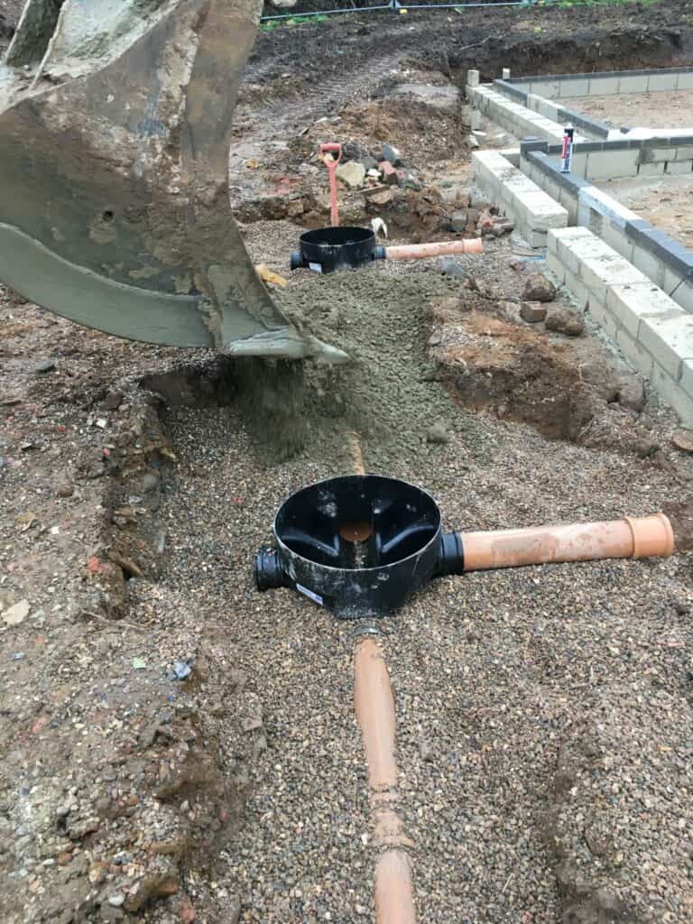 Excavator bucket pouring sand at construction site.