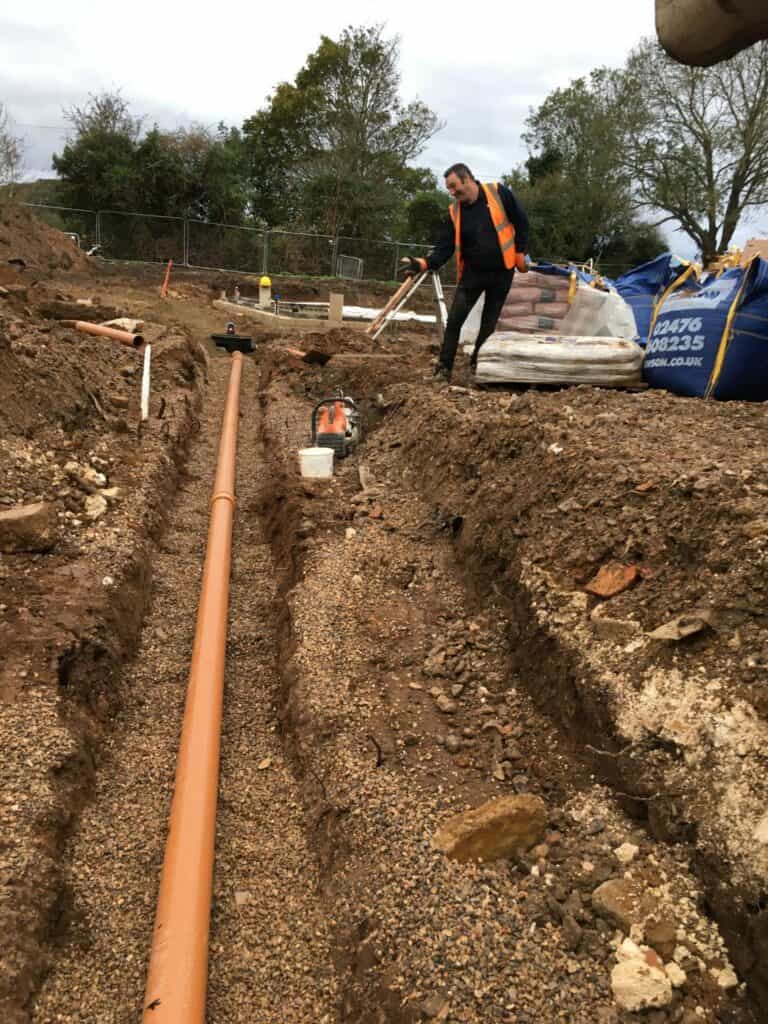 Worker laying pipes at construction site.