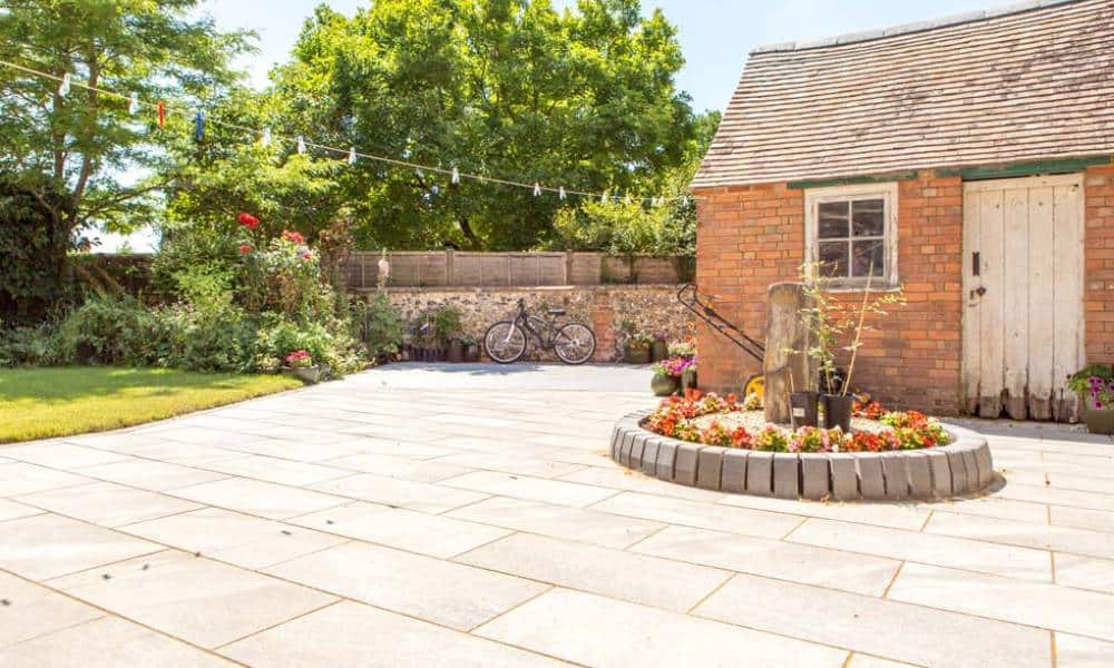 Sunny garden patio with flowerbed and bicycle in UK.