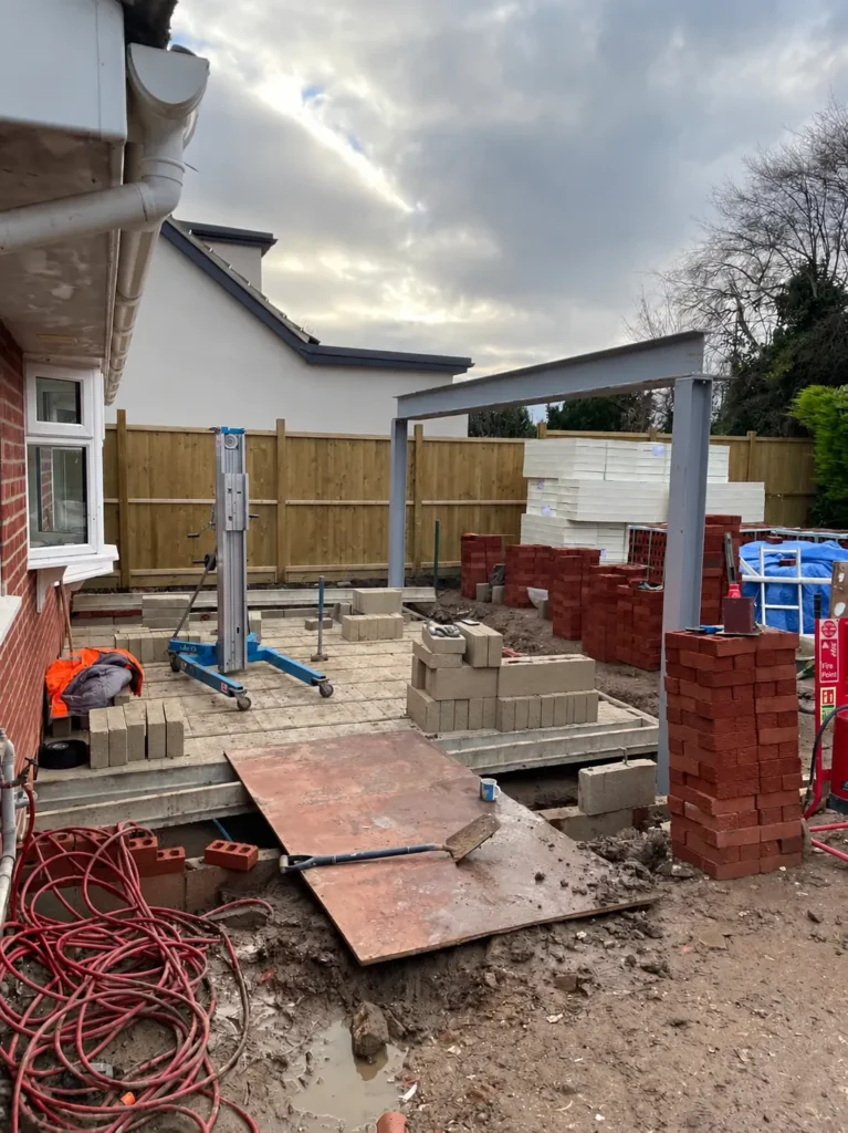 Workers building blockwork beneath a steel frame during residential structural work in King’s Lynn.