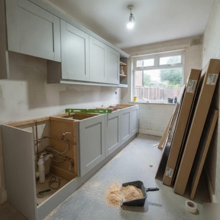 Home renovations in King's Lynn showing a kitchen installation in progress, with grey cabinets, exposed plumbing and building materials on site.