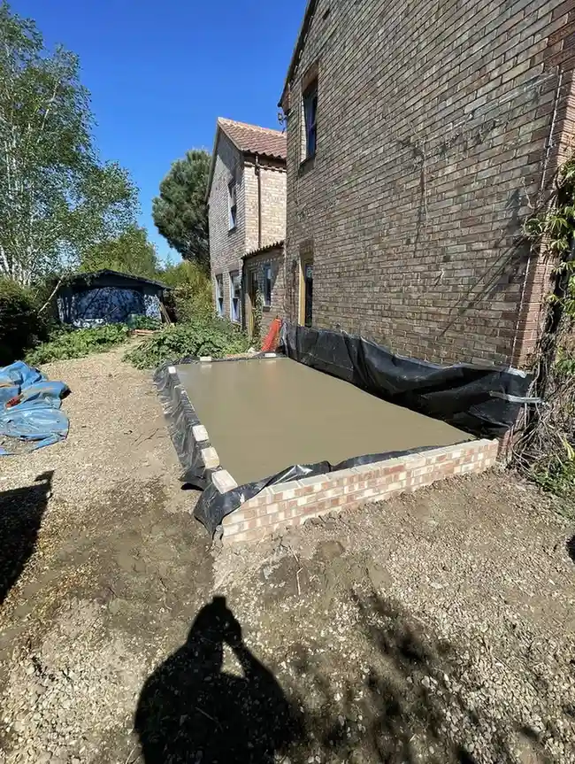 Concrete Services in King's Lynn showing a freshly poured concrete base surrounded by low brickwork.